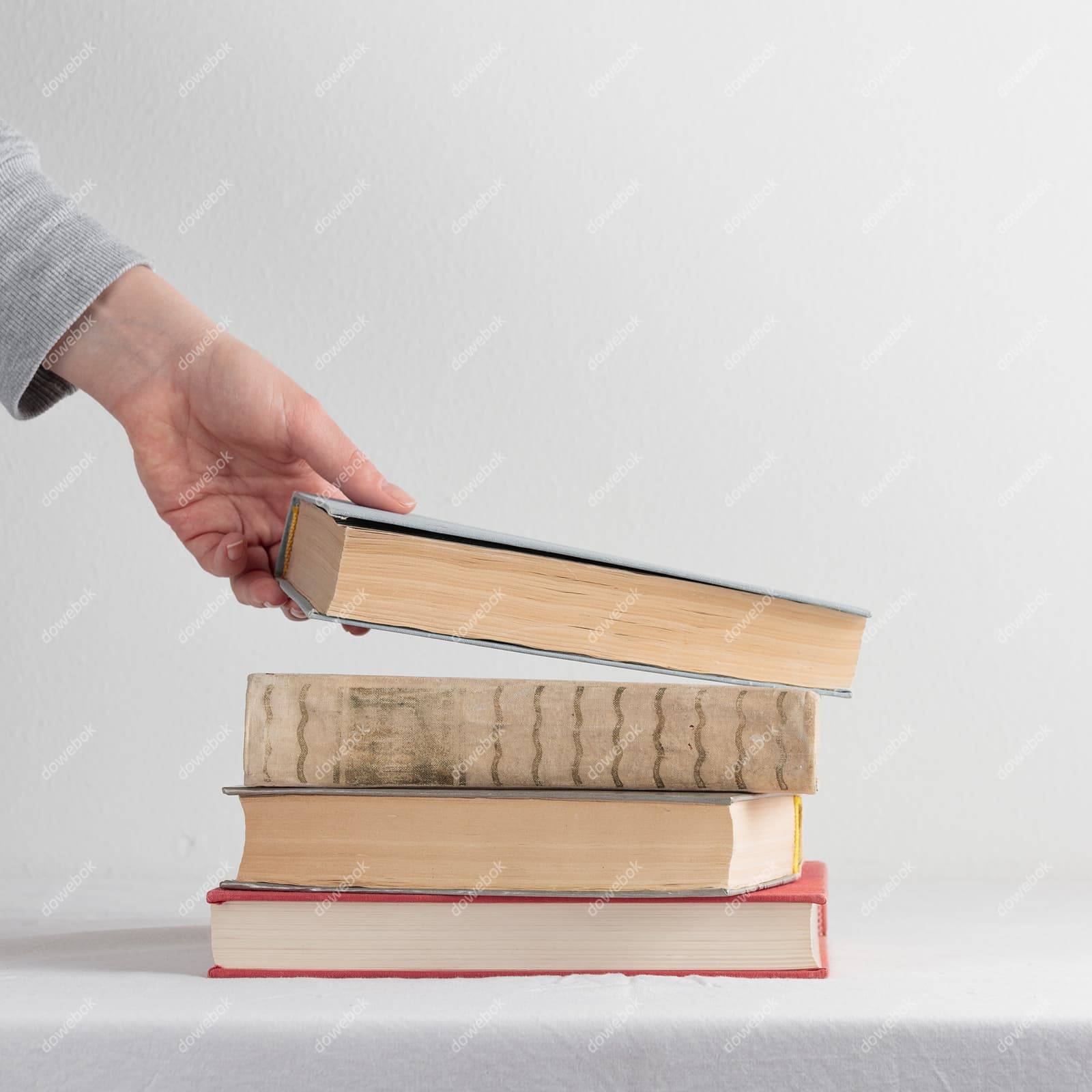 左手拿起桌上的一本书高清图片素材(JPG)