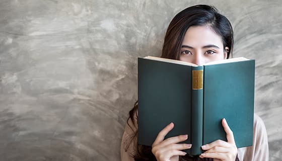 拿着书本挡住半边脸的女孩高清图片素材(JPG)