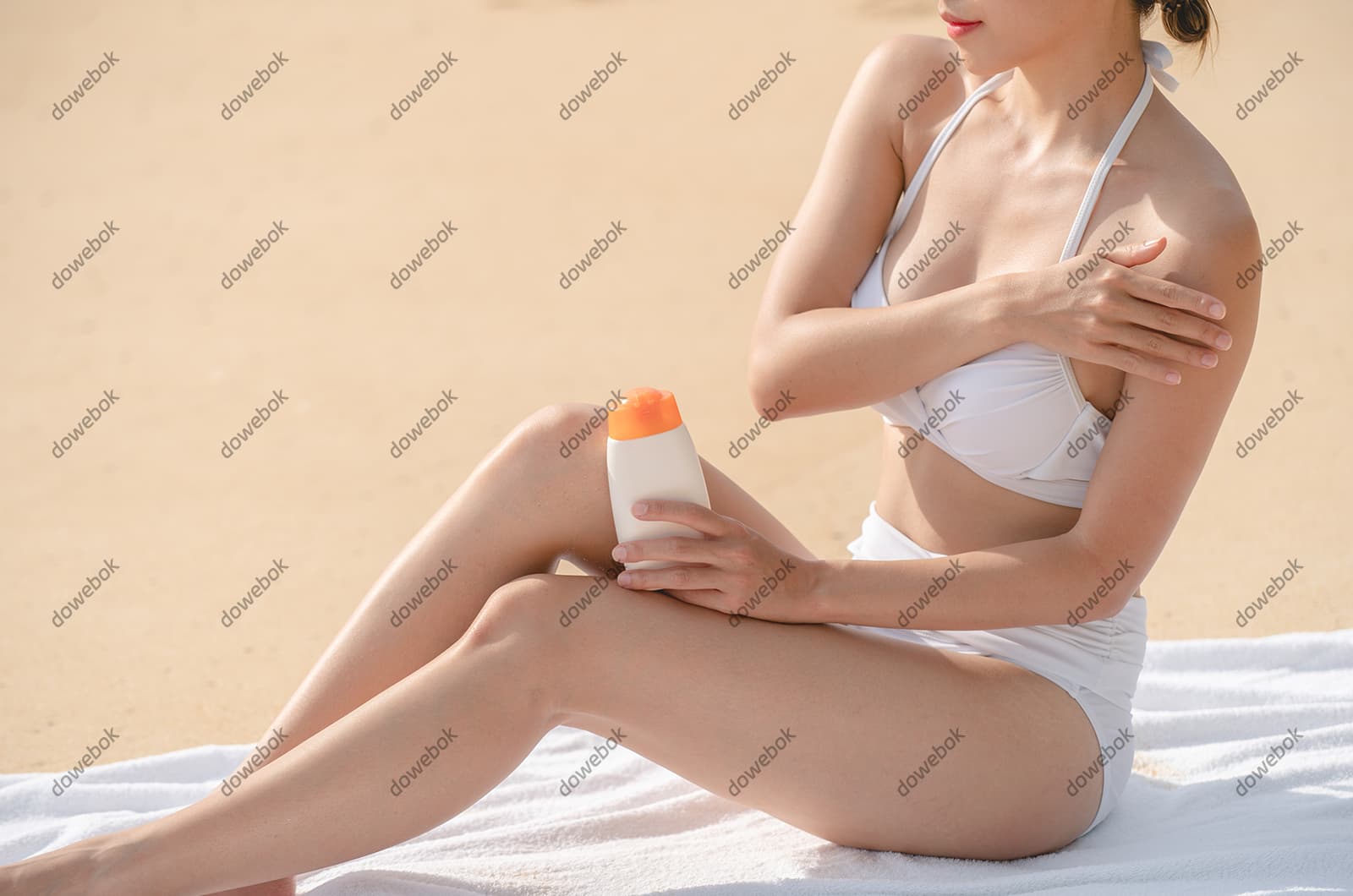 坐在沙滩上涂防晒霜的女子图片素材(JPG)