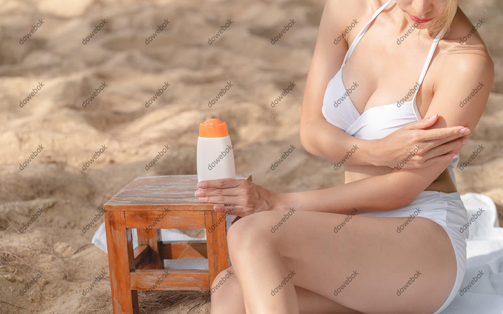 坐在沙滩上涂防晒霜的女子图片素材(JPG)