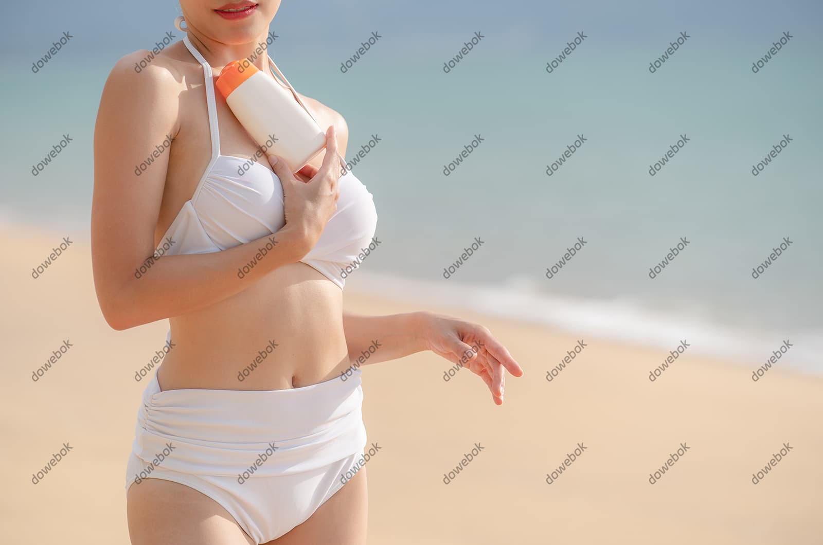 站在沙滩上涂防晒霜的女子图片素材(JPG)