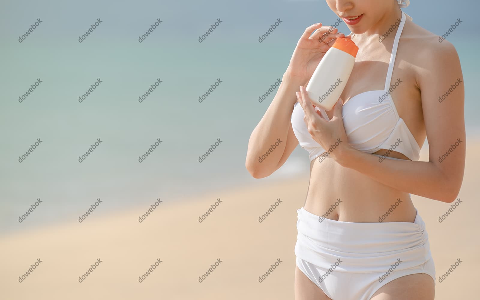 站在沙滩上涂防晒霜的女子图片素材(JPG)