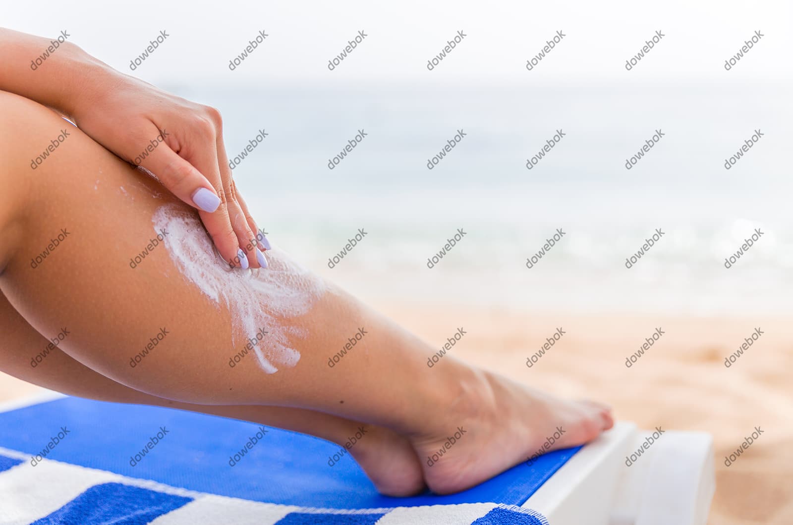 往腿上涂防晒霜的女子图片素材(JPG)