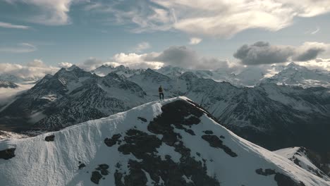 一名男子站在雪上山顶欣赏山景