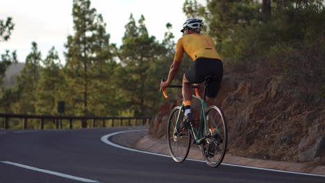 身穿黄色T恤的男子在山路上骑行